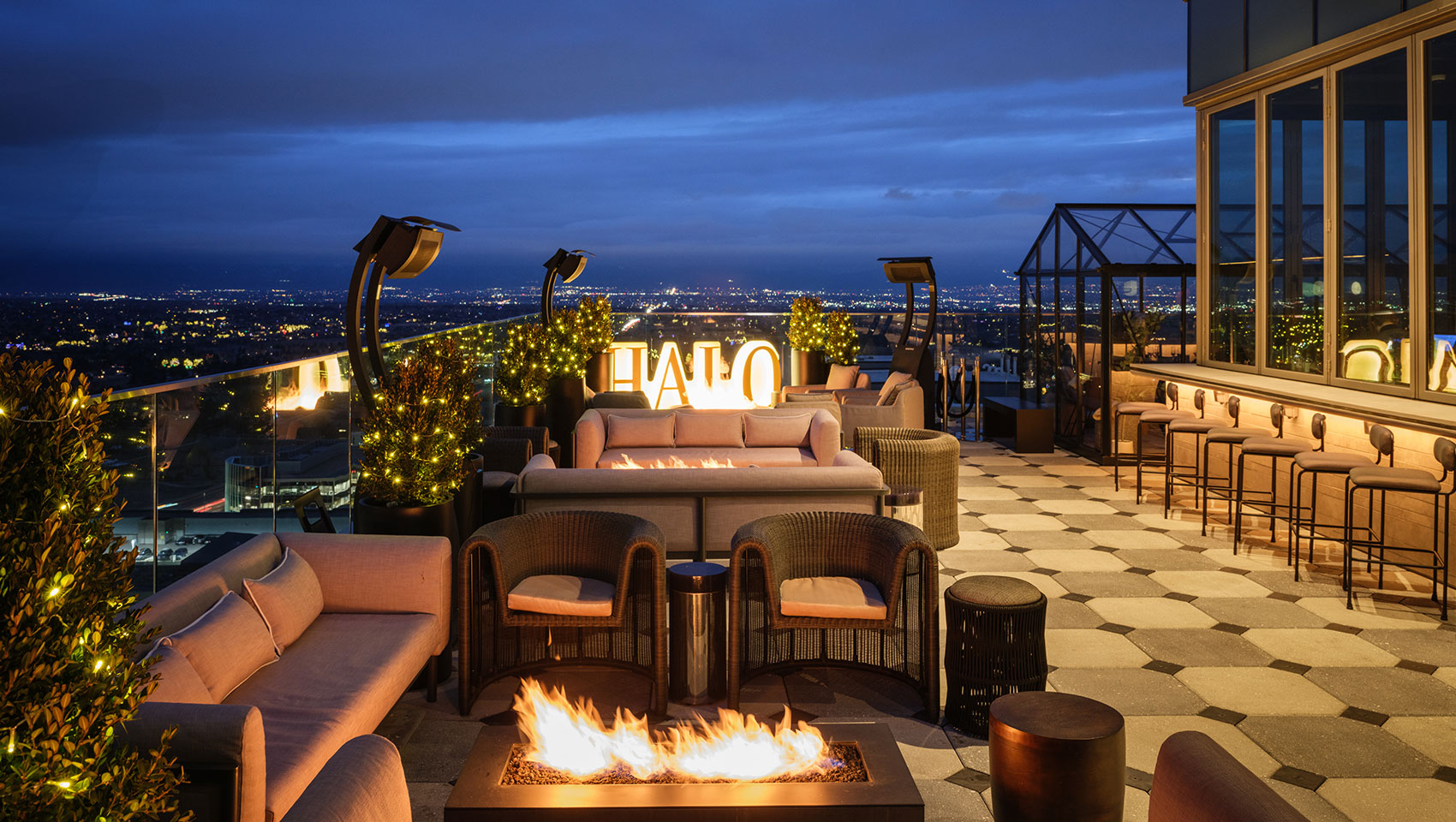 Halo rooftop bar at night with firepits, seating and festively lit trees