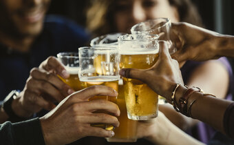 group of hands clinking their pints of beer together in a “cheers” situation